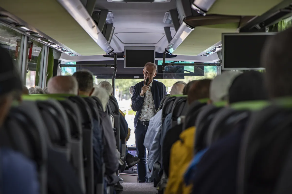 Passengers of boutique river cruise ship MS Thurgau Saxonia (Thurgau Travel) on excursion bus with guide speaking, Berlin, Berlin, Germany