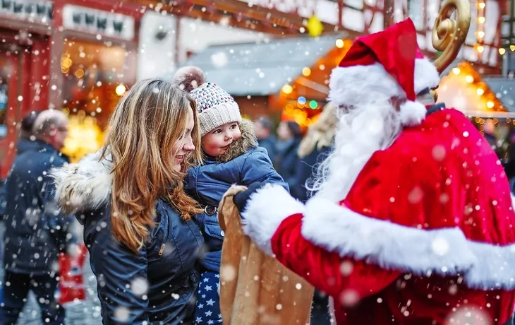 © Irina Schmidt - stock.adobe.com - Kleines Kleinkindmädchen mit Mutter auf Weihnachtsmarkt.